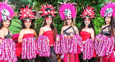 tahitian hula dancers holding purple leis