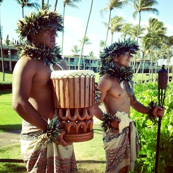 hula entertainers holding hawaiian drum and tiki torch